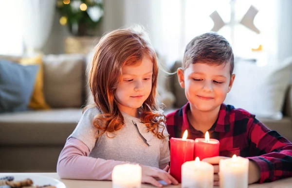 Menina pequena e menino dentro de casa em casa no Natal, segurando velas. — Fotografia de Stock