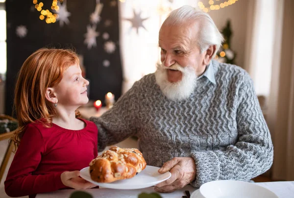 Menina pequena com avô sênior em casa em casa no Natal, falando. — Fotografia de Stock