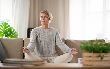 Evde yoga, akıl sağlığı ve meditasyon yapan bir kadının portresi..