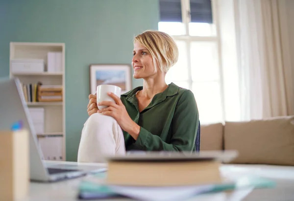 Porträtt av affärskvinna inomhus på kontoret sitter vid skrivbordet, håller kopp te. — Stockfoto