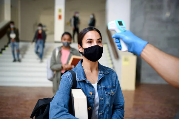 Unga studenter tillbaka på högskola eller universitet, coronavirus och mätning temperatur koncept. — Stockfoto