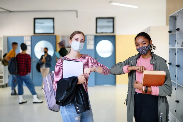 Jóvenes estudiantes amigos con máscaras faciales en la universidad o la universidad, concepto coronavirus. — Foto de Stock