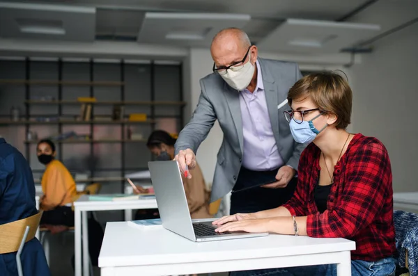 Young students with teacher at desks at college or university, coronavirus concept. — Stock Photo, Image