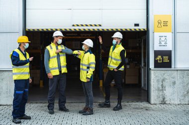 Yüzü maskeli bir grup işçi deponun önünde karşılama yapıyor, koronavirüs konsepti..