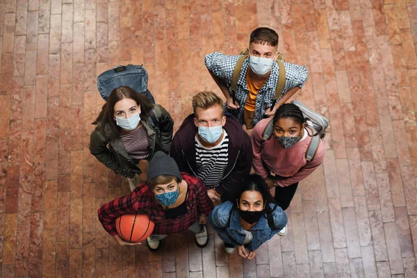 Visão superior de jovens estudantes com máscaras faciais na faculdade ou universidade, conceito de coronavírus. — Fotografia de Stock