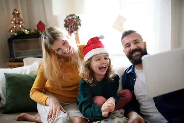 Família com filha pequena dentro de casa no Natal, tendo videochamada. — Fotografia de Stock