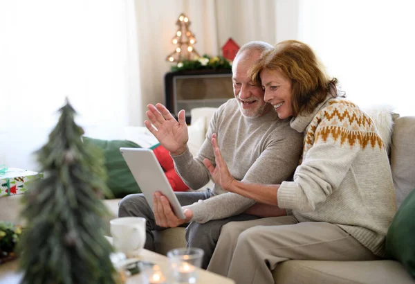 Vista laterale della coppia anziana in casa a Natale, con videochiamata con la famiglia. — Foto Stock