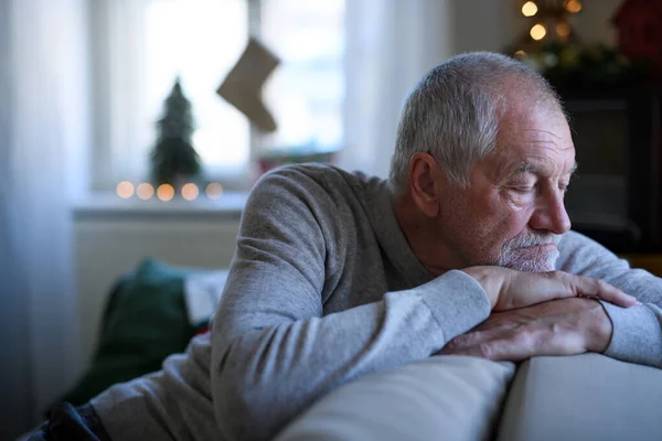 Einsamer älterer Mann, der zu Weihnachten auf dem Sofa sitzt und schläft. — Stockfoto