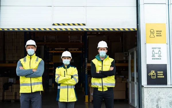 코로나 바이러스, 창고 앞에 얼굴 마스크를 하고 있는 노동자들의 그룹. — 스톡 사진