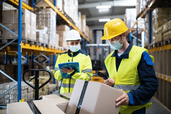 Arbeiter mit Mundschutz arbeiten drinnen im Lager, Coronavirus-Konzept. — Stockfoto