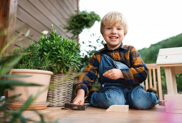 Retrato de menino pequeno ao ar livre na mesa construindo casa de pássaros, projeto diy. — Fotografia de Stock