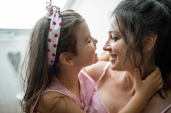 Mãe e filha pequena dentro de casa, abraçando. — Fotografia de Stock