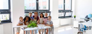 Küçük çocuklar ve öğretmenler sınıfta bahçe işleri yapıyor. Fen dersi..