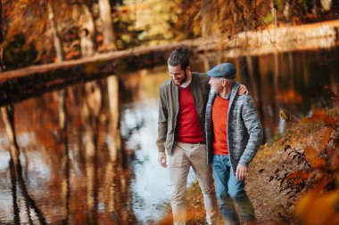 Kıdemli baba ve küçük oğlu doğada yürürken, konuşuyor.
