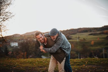 Kıdemli baba ve küçük oğlu doğada yürürken, eğleniyor.