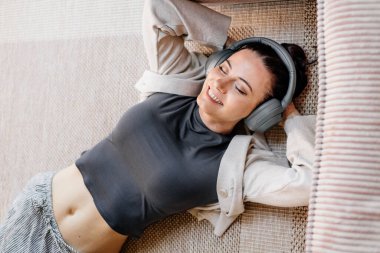 Kadın evde dinleniyor, işten sonra müzik dinliyor. Kişisel bakım anı.