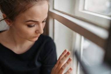 Depresyonda olan genç bir kadın pencerenin kenarında tek başına oturuyor..