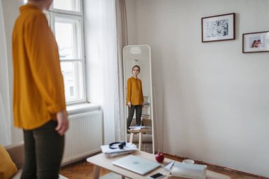 Depresyondaki kadın aynada kendine bakıyor, kanepede duruyor..