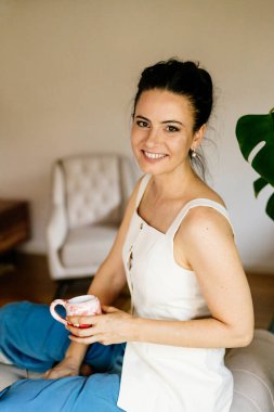 Bir kadın dinleniyor ve kahve içiyor, evde huzurlu bir an..