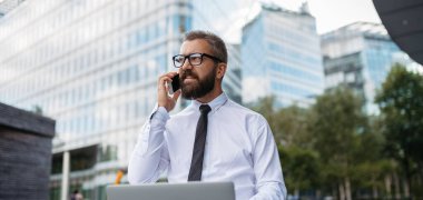 Parkta çalışan yakışıklı bir iş adamı ve müşteriyle telefon görüşmesi yapıyor..