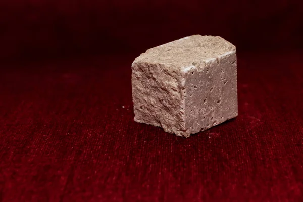 Грубый Каменный Куб Изолирован Размытом Красном Фоне Фокус Камне — стоковое фото
