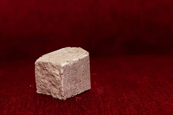 Грубый Каменный Куб Изолирован Размытом Красном Фоне Фокус Камне — стоковое фото