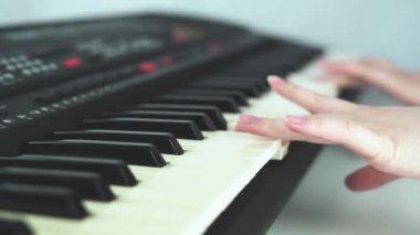 Klavye, piyano çal. Yavaş çekimde yakın çekim. Piyano çalan iki el, klavye.