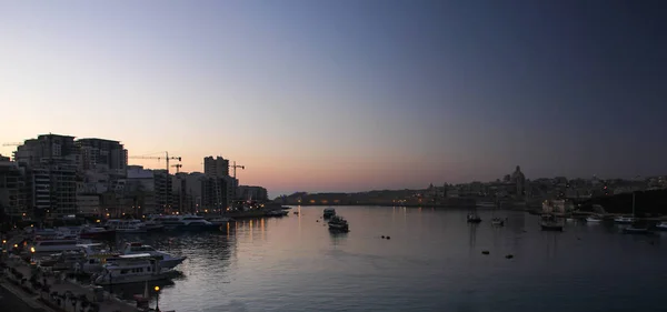 Karanlık gecenin panoramik manzarası ve Valletta Büyük Limanı 'nda şafağın çok erken başlaması.