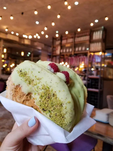 Big cookies with berries and green glaze in hand in cafe