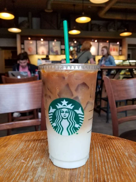 Soğuk kahve latte arka plan üzerinde kişi ile Starbucks kafede plastik bardak — Stok fotoğraf