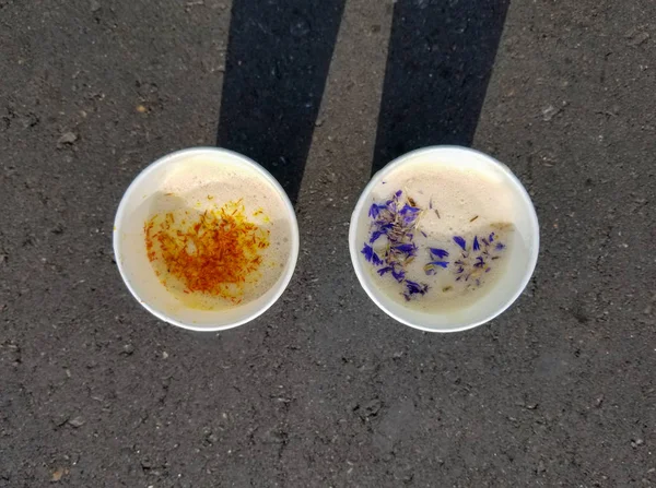 Dos tazas de café con acianos y azafrán de pie sobre asfalto con sombras — Foto de Stock
