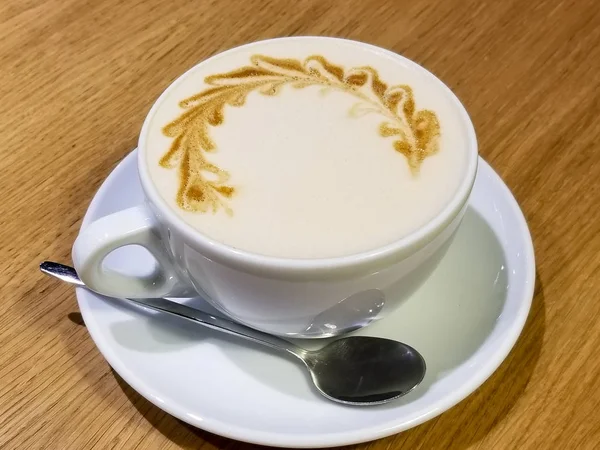 Taza de café con latte arte en la mesa de madera de cerca —  Fotos de Stock