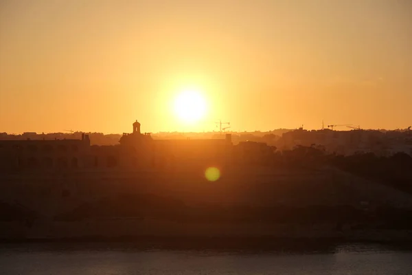 Turuncu günbatımı güneş diski silhouette şehir kuleleri ve İnşaat vinçleri yukarıda olan