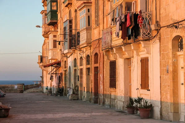 Skutečný život na ulici Valletta během orange sunset - nikdo na chodník a sušák na typické maltské balkonu — Stock fotografie