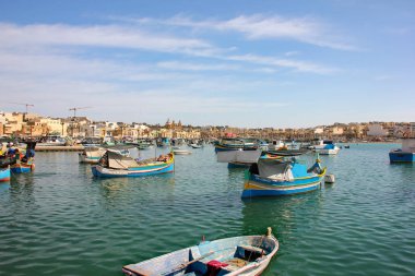 Marsaxlokk, Malta - Mayıs 2018: Panoramik geleneksel gözlü tekneler luzzu güneşli gün ile balıkçı köyü