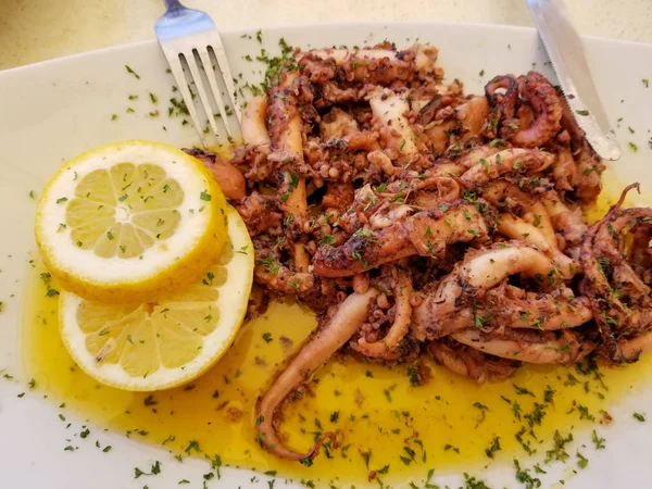 Limon ve baharat çatal ve bıçak Marsaxlokk, Malta yaz sokak kafede beyaz tabakta Fried ahtapot