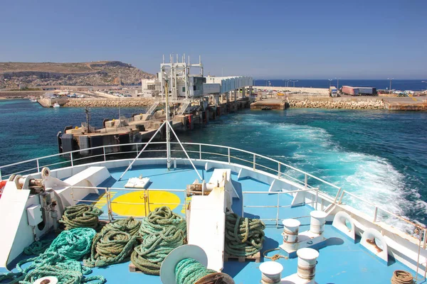 Mavi deniz suyu üzerinde Cirkewwa feribot terminaline ile dalgalar kıyıdan feribot kalkar. Tahta görüntülemek