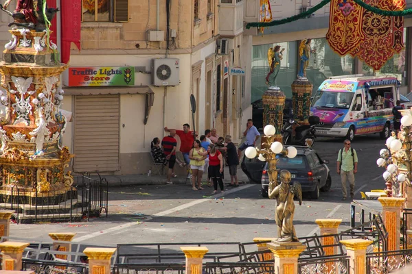 Marsa, Malta - 2018 olabilir: Turistler ve yerel halkın festively bekleyen Meydanı bayrakları ve heykeller ile güneşli gün yıllık festa dini tatil için dekore edilmiştir. Yerdeki renkli konfeti