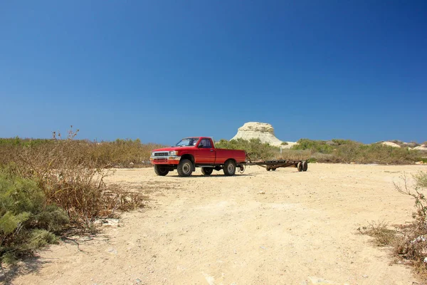 Kırmızı kamyonet boş römork üzerinde arka planda parlak güneşli bir günde küçük bir kaya ile çölde ile