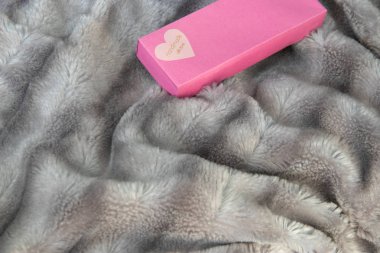 Gümüş gri tüylü faux kürk battaniye arka plan üzerinde aşkın büyük pembe hediye kutusu ile bir kalp. Aşk kalp ile etiket el yapımı