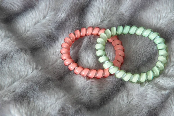 Roze en groen blauw scrunchy haar binden elastische voorjaar op de achtergrond van de deken zilver grijze fluffy namaakbont — Stockfoto