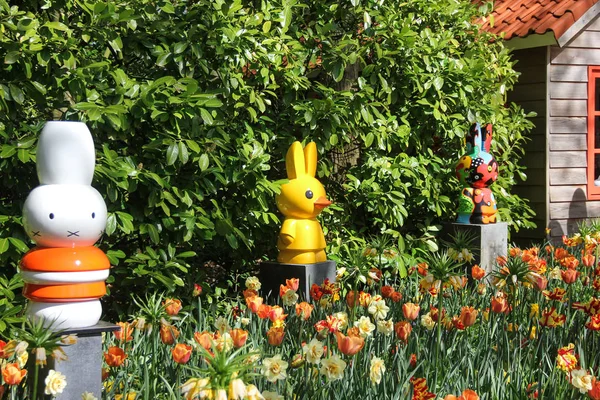 Komik heykel oyuncaklar bunny alan sarı, turuncu ve kırmızı güzel laleler ve yeşil ağaçlar kapatın. Bahar zaman Keukenhof Çiçek Bahçesi