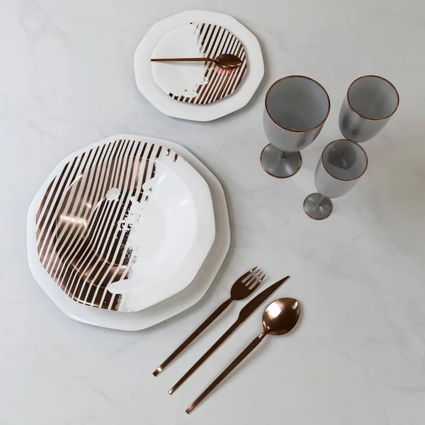 A beautiful set of dishes with a gold pattern. Plates, glasses, spoons, fork, knife on the table. 3D illustration.