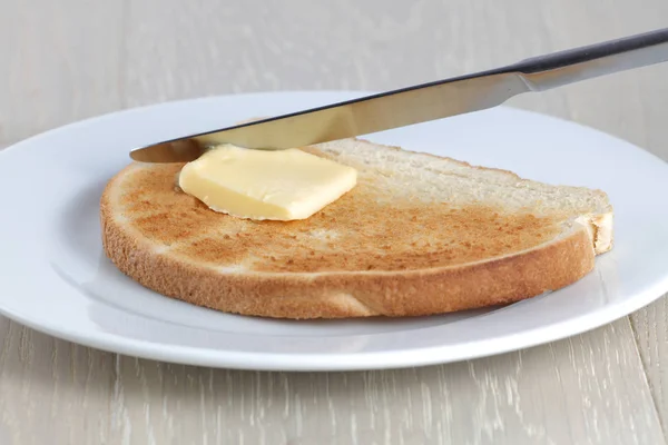 Beyaz bir tabakta tost bıçağı ve tereyağı — Stok fotoğraf