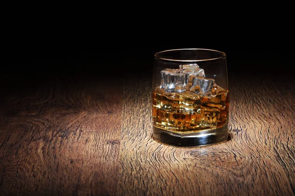Scotch in bicchiere di vetro con rocce di ghiaccio sulla vecchia superficie di legno — Foto Stock