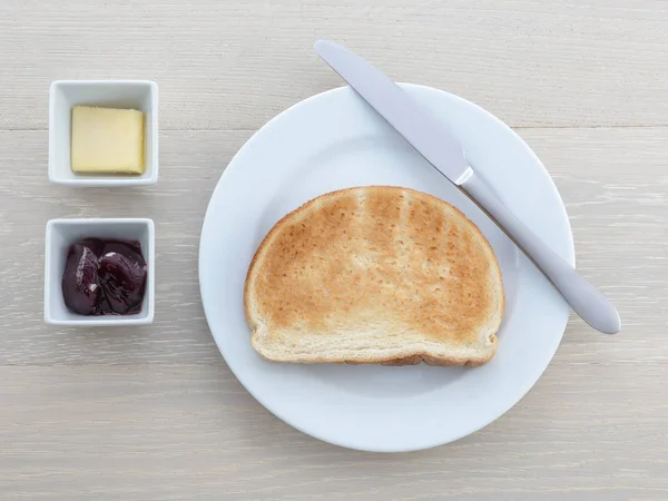 Ahşap masada kahvaltı tabağı tost bıçağı tereyağı reçel jöle — Stok fotoğraf