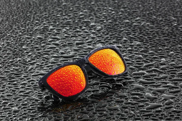 Orange sunglasses with water droplets on wet surface — Stock Photo, Image