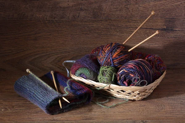 Tejer y lana en una cesta sobre una superficie de madera — Foto de Stock