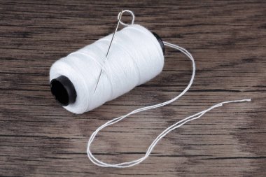 Beyaz pamuk makarası ve ahşap üzerinde iğne