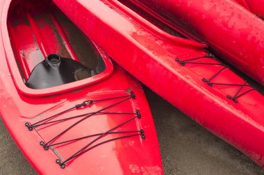 Boş kırmızı plastik eğlence kayaks Kiralık veya Kiralık, yağmurlu bir günde tarihinde saat sonra kumsalda depolanan. Hilal Beach, Surrey, British Columbia, Kanada.